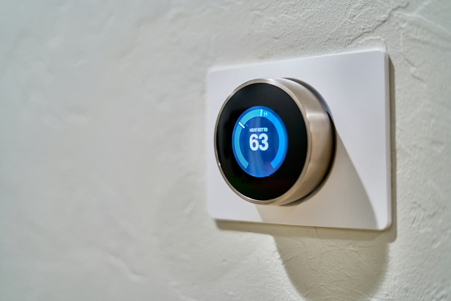 Smart thermostat on a white wall showing the room temperature